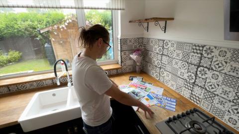 Man looking at political leaflets on a kitchen side
