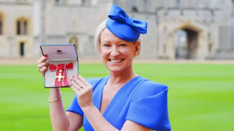 PA Media Ruth Dodsworth mengenakan gaun biru dan topi biru