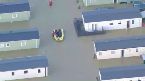 An aerial image of Billings Aquadrome, static homes are surrounded by water and a rescue boat passes through