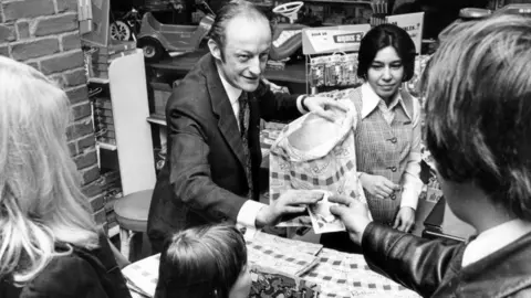 Two women, a man and a child buying toys in the toy department of Rackhams, Birmingham, West Midlands. December 1974. 