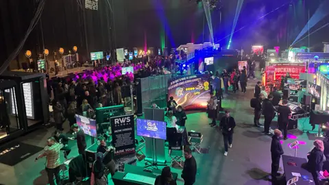 Production Park, filled with young people and screens lit up in multi colours.