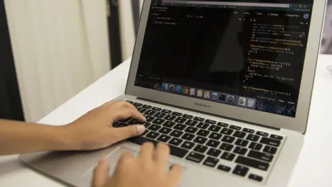 Bloomberg via Getty Images Two hands are typing code on a grey MacBook Air.