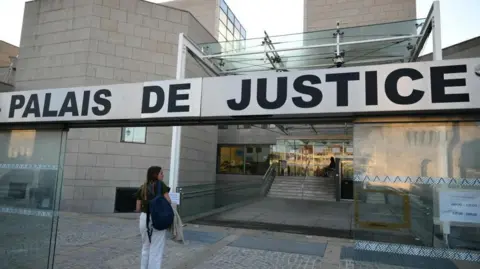 A woman walks towards an Avignon courthouse on 2/9/2024 where a trial was set to begin of a man accused of drugging his wife for nearly ten years and inviting strangers to rape her.