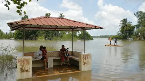 AFP Women at a flooded bus stop