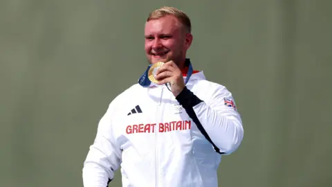 PA Media Great Britain's Nathan Hales with his gold medal following the Men's Trap Final at the Chateauroux Shooting Centre on the fourth day of the 2024 Paris Olympic Games in France.