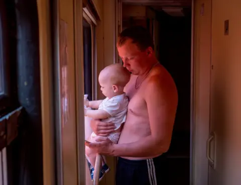 Peter Dench A man and a baby try to cope with the heat during their journey