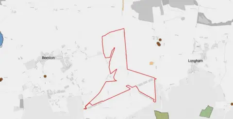 Breckland Council A greyscale map showing a red-outlined site boundary across rural farmland between Beeston and Longham. The outlined area follows irregular field edges and tracks, with nearby roads, scattered buildings, and several marked points of interest visible around the perimeter.