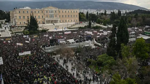 Getty Images Greeks stand in the rain in the centre of Athens 