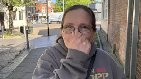Woman holds her nose.