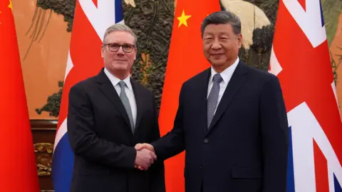 Sir Keir Starmer and Chinese President Xi Jinping shake hands in front of British and Chinese flags.