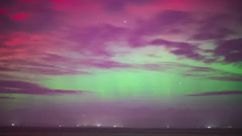 Mark Griffiths The horizon over Heysham, the sky glows green, purple and red