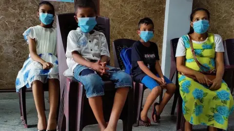 A pregnant woman sits down with her three children at a community kitchen in Sri Lanka