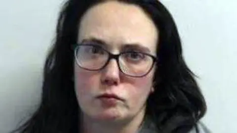 Police mugshot of Claire Kilduff who has dark hair and glasses.