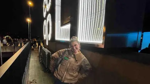 Amber Musgrove-Benford Girl stood outside at Co-op Live Arena. There are bright lights and she is smiling.