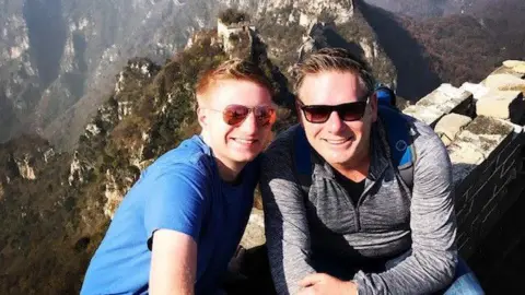 Hall family Sam Hall and his dad Chris sitting on the Great Wall of China