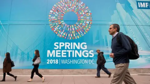 AFP People walk past the IMF headquarters during the 2018 spring meetings of the International Monetary Fund and World Bank in Washington