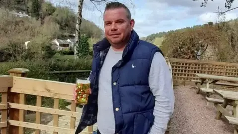 Marcus Dunkerton holding a pint in a pub garden