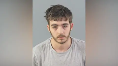 Carlo Tritta, who is wearing a grey jumper, is staring directly at the camera in this prison mugshot. 