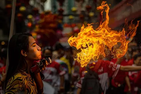 Gambar Ezra Acayan/Getty Images, pemain bernafas api selama distrik Binondo, Filipina.