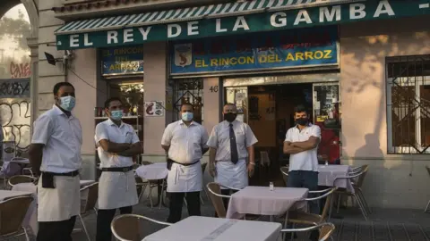 Getty Images The staff of El Rey de la Gamba 2 restaurant poses for photos outside their restaurant on July 27, 2020 in Barcelona, Spain