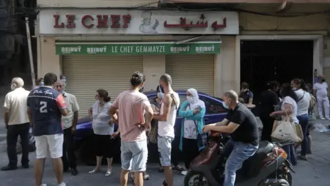 Getty Images People stand outside the shuttered Le Chef restaurant on 13 August 2020