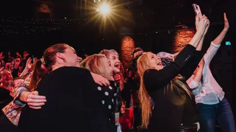 Ingrid Muir Collette takes a selflie with the crowd at at Cottiers Theatre gathered behind her.