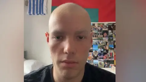 Supplied Charlie looking at the camera with a football shirt and photos behind him