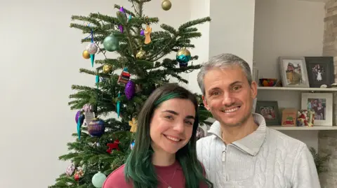 Sophia and Serg by a Christmas tree