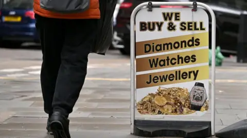 Getty Images A person walks past a sign that reads "We buy and sell diamonds, watches, jewellery".