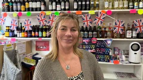 A woman standing inside a post office in Youlgreave, Derbyshire