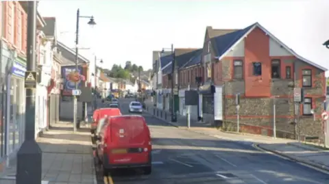 Photo of Blackwood High street with a Royal Mail red post van parked on the left hand side and shops visible either side