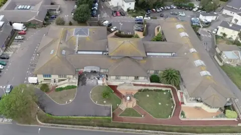 BBC An aerial view of a T-shaped building with a walkway and parking surrounding it.