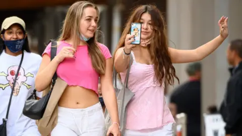 People take a selfie while shopping in SoHo, New York