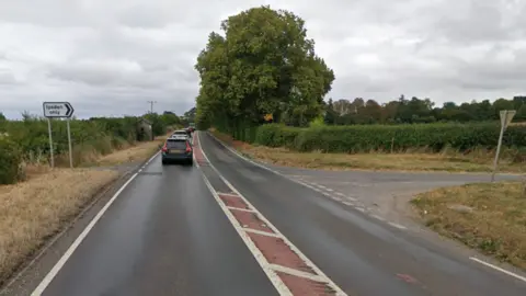 A fairly straight single carriageway has a sign pointing to a right turn, with the words "Ipsden only"