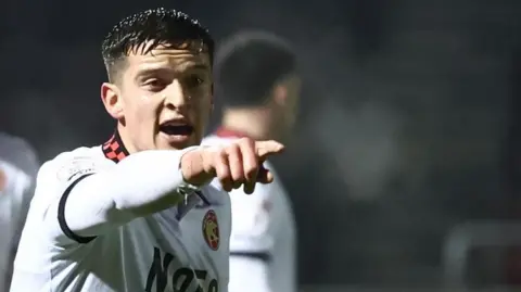 Harrison Burke points a directs a team-mate during a game for Walsall