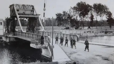 PA Media Troops crossing Pegasus Bridge - a black and white photo from 1944