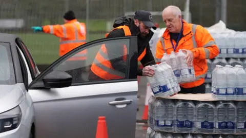 Workers hand over bottled water at a water station in East Grinstead.