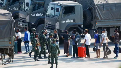 Thai News Pix Released foreign workers line up outside military trucks to be taken to the Thai side of the border with Myanmar