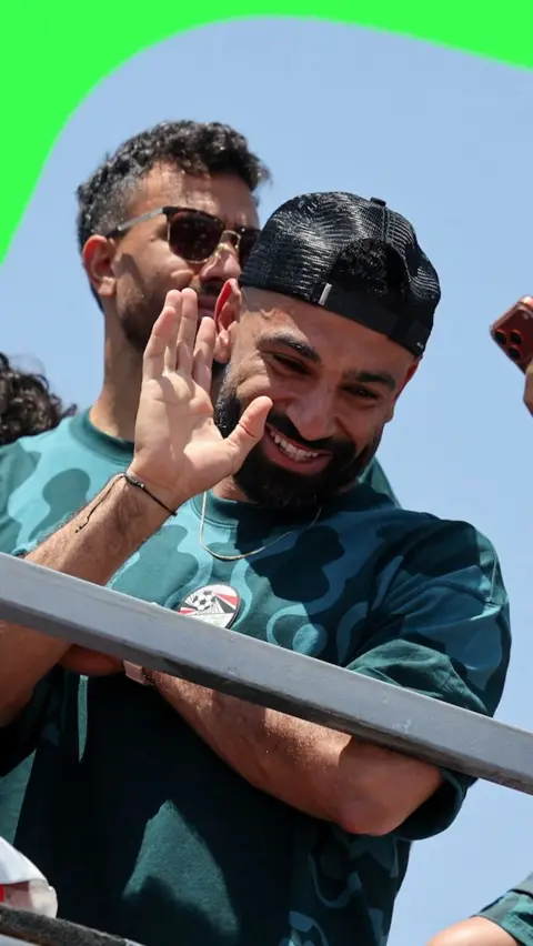 A close up of Mohamed Salah waving down to fans from the Egypt players bus