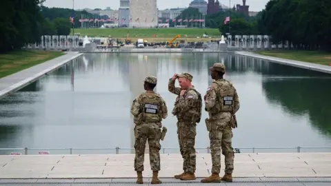 Three members of the National Guard stand in front of the Reflecting Pool