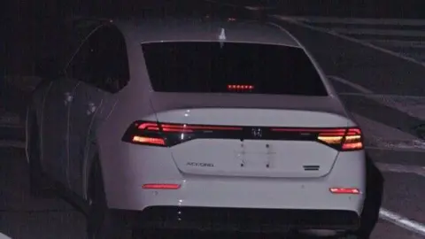 Toronto Police Services A white Honda Accord, seen from behind in dim light, with no licence plate