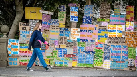 PA Media woman walking past thank you nhs signs