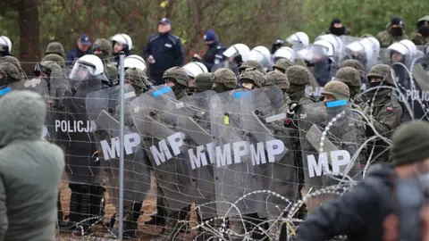 Getty Images Polish troops and border guards with shields stop migrants from crossing into the country