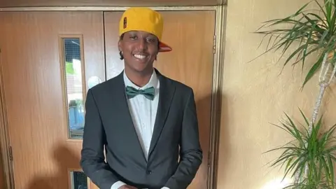 Family handout Eddie Kinuthia smiling in a bowtie and yellow cap