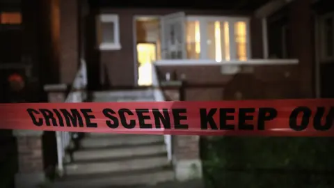 Getty Images Crime scene tape is stretched around the front of a home where a man was shot in Chicago, Illinois, on 28 May 2017