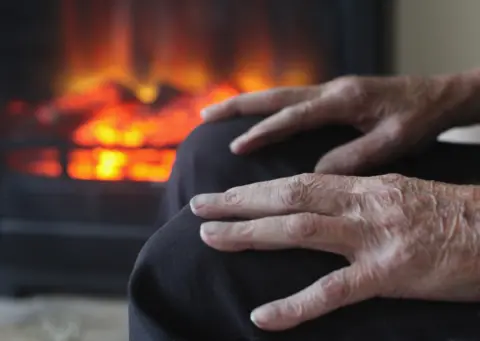 Getty Images elderly person's hands, sitting by fire