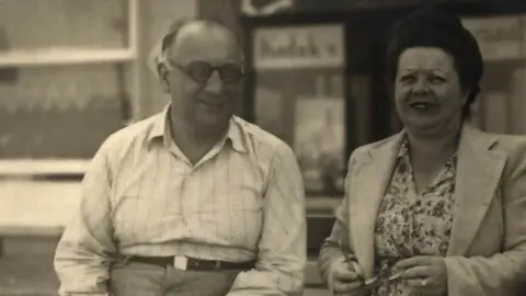 Vermeirsch family A photo of Theo (left) and Esther Vermeirsch, original owners of the Patisserie Valerie, Esther was known around the Soho area as Madame Valerie and never worked in the kitchen baking, but ran the front of house. The photo was taken in 1946, a year before Theo died, at an unknown location.