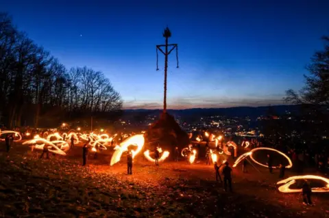 INA FASSBENDER/AFP People light the Easter fire with burning torches on a hill in Attendorn, western Germany on April 9, 2023.