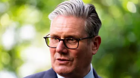 Keir Starmer looking to the side of the camera, wearing a navy suit