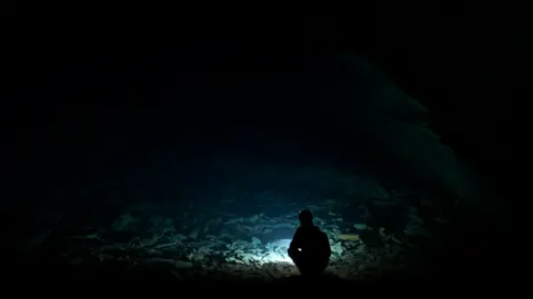 Flooded part of the mine - with member of staff silhouetted against the water in a chamber